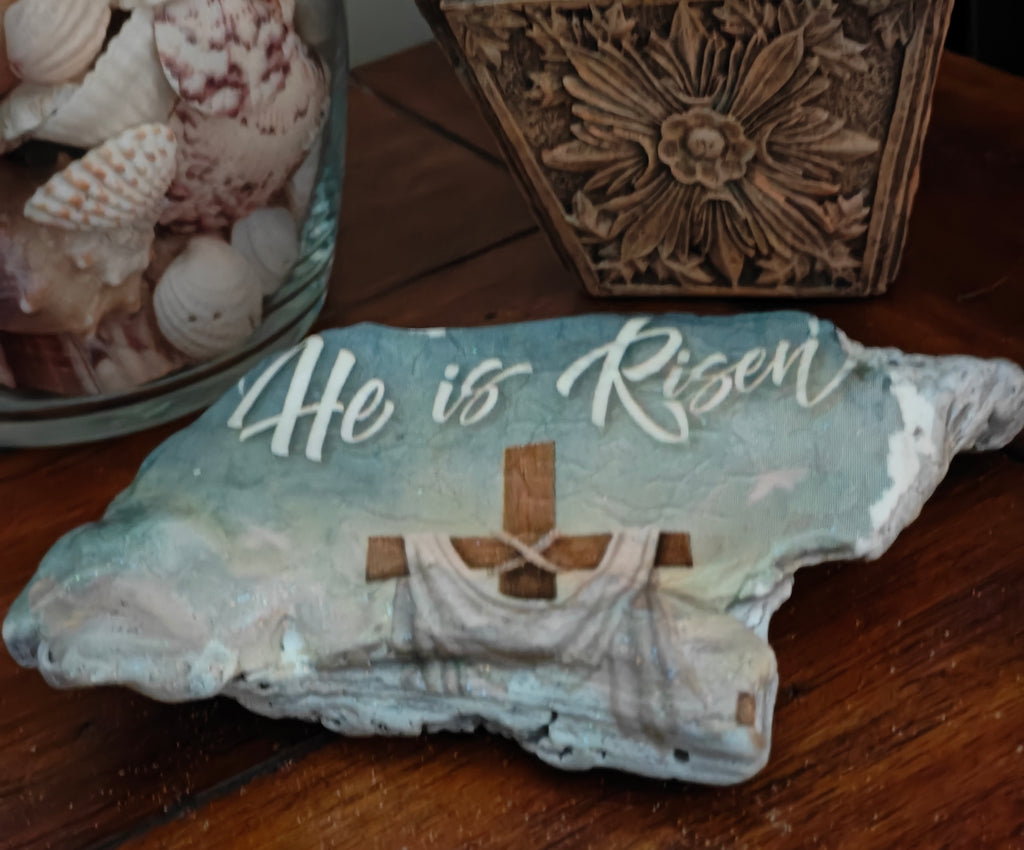 “Hand‑decorated small natural shell featuring the message ‘He Is Risen’