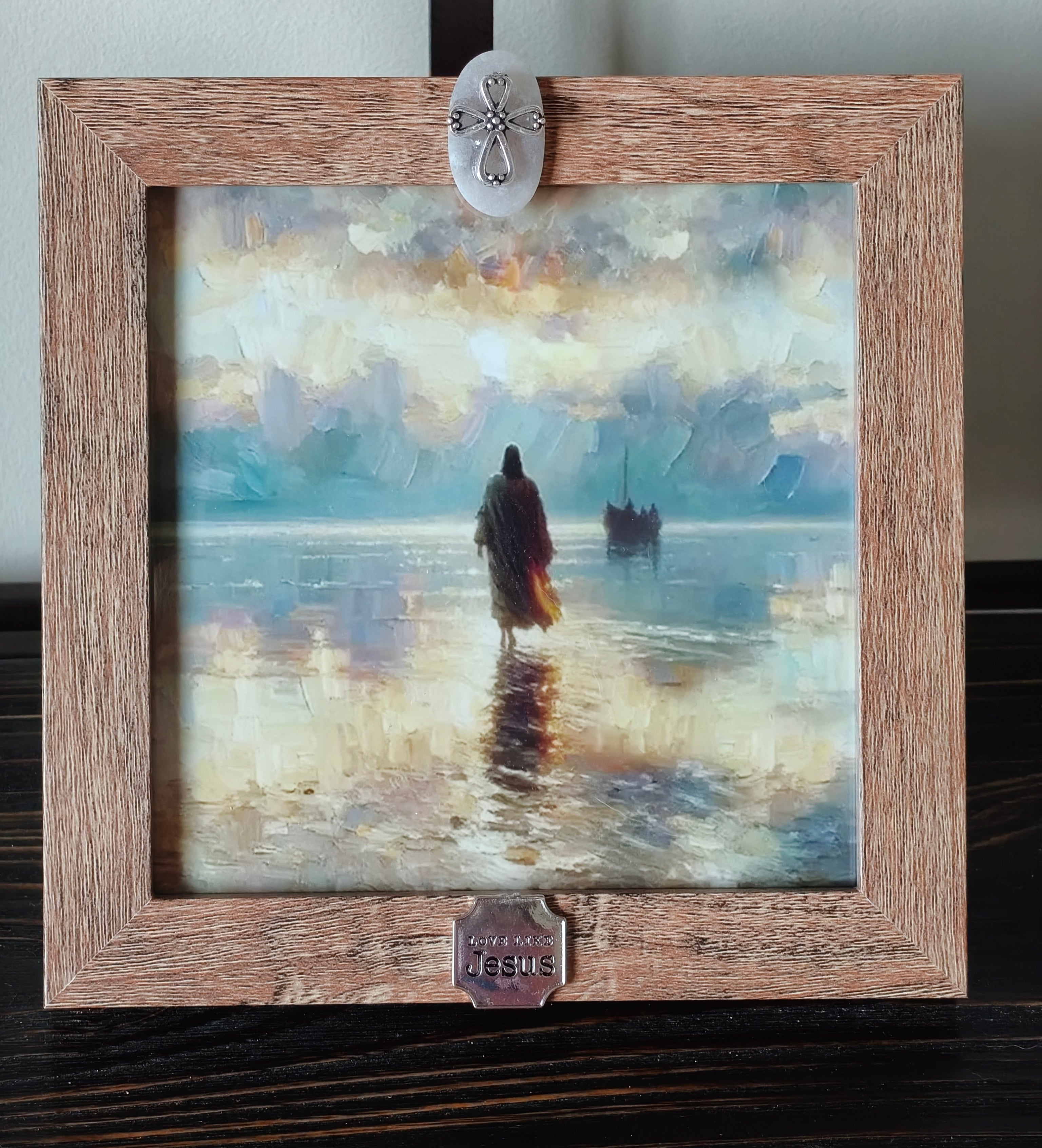 “Light brown framed picture featuring Jesus walking on the water, in soft pastels.